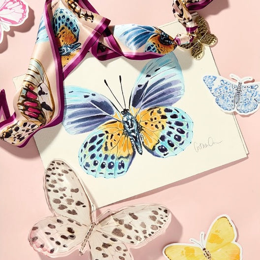 Butterfly-themed accessories including scarf and stickers on a pink background
